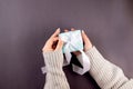 female hands holding light blue gift box with white ribbon on dark grey background. My hands cradle a pastel blue gift box Royalty Free Stock Photo