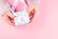 female hands holding light blue gift box with white ribbon on pink background. My hands cradle a pastel blue gift box Royalty Free Stock Photo