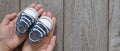 Female hands holding little baby shoes banner, tiny sneakers in mom`s palms, happy mom`s day concept, waiting for baby backgroun Royalty Free Stock Photo