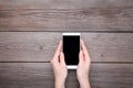 Female hands holding mobile phone with blank screen on grey wood background. Smartphone on wood table Royalty Free Stock Photo