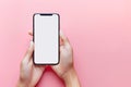 Female hands holding mobile phone with white empty screen in front of pink background with copy space Royalty Free Stock Photo