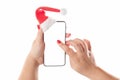 Female hands holding mobile smart phone with santa hat isolated on white background. Blank white screen. Concept of Christmas Royalty Free Stock Photo