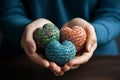 Female hands holding multicolor hearts on wooden table, closeup Ai generative