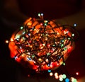 Female hands holding Multicolored Christmas light decorations on dark holiday background. Xmas and New Year theme. Royalty Free Stock Photo