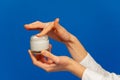 Female hands holding open cosmetic cream container