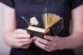 Female hands holding open vintage prayer book and pink carnation flower on a black background Royalty Free Stock Photo