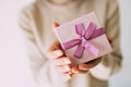 Female hands holding gift box with pink ribbon.