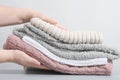 female hands holding a pile pastel color jumpers and other knitted clothing. winter apparel, trendy pale textured