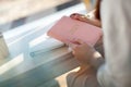 Female hands holding pink coral coloured leather diary 2021 while sitting near a window at cafe Royalty Free Stock Photo