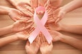 Female hands holding pink ribbon on wooden background, top view. Breast cancer awareness concept Royalty Free Stock Photo