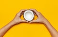 Female hands holding ripe coconut on yellow colored background, minimal flat lay style top view with copy space. Pop art design, c Royalty Free Stock Photo
