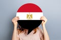 Female hands holding a round information piece of paper dialog with Egypt Flag isolated over grey studio background