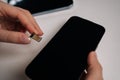Female hands holding sim card and new smartphone on white table, preparing for inserting sim card and activating mobile Royalty Free Stock Photo