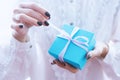 Female hands holding a small gift wrapped with pink ribbon. Small gift in the hands of a woman indoor Royalty Free Stock Photo