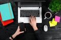 Female hands holding a smart and typing on the keyboard of a laptop on black wooden table. Royalty Free Stock Photo