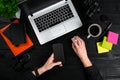 Female hands holding a smart and typing on the keyboard of a laptop on black wooden table. Royalty Free Stock Photo