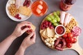 Female hands holding snacks from a round charcuterie board on a gray background, party a appetizer Royalty Free Stock Photo