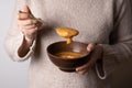 Female hands holding a spoon and a bowl of red lentil cream soup Royalty Free Stock Photo