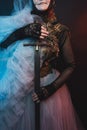 Female hands holding a sword, cropped photo. Fabulous creature, historical character, fantasy queen, witch, in a fairy costume. Wo Royalty Free Stock Photo