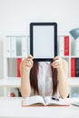 Female hands holding tablet in front of her face with copy space for text or picture. Stylish modern office workplace on