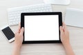 female hands holding a tablet with a isolated screen over a table Royalty Free Stock Photo