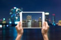 Female hands holding tablet taking pictures cityscape Modern building river side on twilight time,Thailand