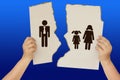 Female hands holding a torn poster separating the symbol of a man and a woman with children, the concept of a breakup, divorce, Royalty Free Stock Photo