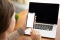 Female hands holding touch phone with isolated screen above the table with laptop in the office Royalty Free Stock Photo