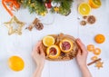 Female hands holding tray with unusual Christmas mulled wine served in orange. Hot winter drink on the wooden table with christmas