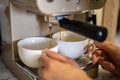 Female hands holding two white porcelain cups cooking fragrance aroma morning coffee in machine
