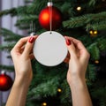 female hands holding white blank christmas ball on tree background, AI Generated Royalty Free Stock Photo