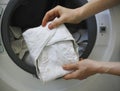 Female hands holding a white cloth baby diaper in front of a washing machine full of cloth bamboo washable diapers