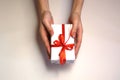 Female hands are holding a white gift box with a red ribbon. Christmas and New Year or season greetings. Selective focus Royalty Free Stock Photo