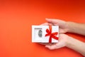 Female hands holding a white gift box with a steel model of a human brain inside and a red bow on the cover. Creative present