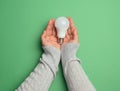 Female hands holding white glass lamp, green energy Royalty Free Stock Photo