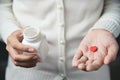 Female hands is holding a white pill bottle and a red pill in he Royalty Free Stock Photo