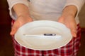 Female hands holding a white plate with an electronic thermometer, an offer to measure the temperature