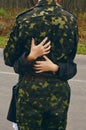 Female hands hug a man in camouflage uniform. Relations with the military, love on a melt Royalty Free Stock Photo