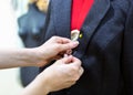 Female hands with a jacket and a pin, close up. Tailor makes a fitting on mannequin, selective focus.