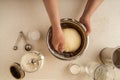 Female hands kneading dough in a bowl on tabletop. Various kitchen utensils, ingredients. Top view Royalty Free Stock Photo