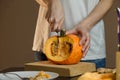 Female hands with knife chopping pumpkin on cutting board. Preparing autumn vegetables. Royalty Free Stock Photo