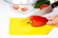 Female hands with a knife cut red pepper on a yellow cutting board Royalty Free Stock Photo