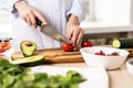 Female hands with knife in the kitchen, slicing red tomato for salad Royalty Free Stock Photo