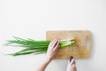 Female hands with a knife, slicing vegetables on a wooden board on a white background. Royalty Free Stock Photo
