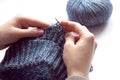 Female hands with knitting needles to knit wool sweater on white background