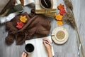 Female hands knitting sweater on the floor with autumn leaves and cup of coffee