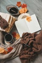 Female hands knitting sweater on the floor with autumn leaves and cup of coffee