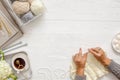 Female hands knitting with white wool, on a wooden background, top view. Handicraft accessories, tea, diary and