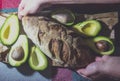 Female hands laying bread near the avocado.