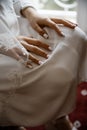 Female hands laying on her knees.She is wearing her white wedding gown